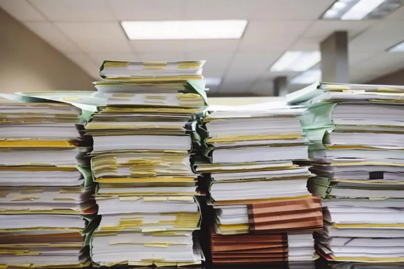 Stacks of paper documents and file folders on shelves